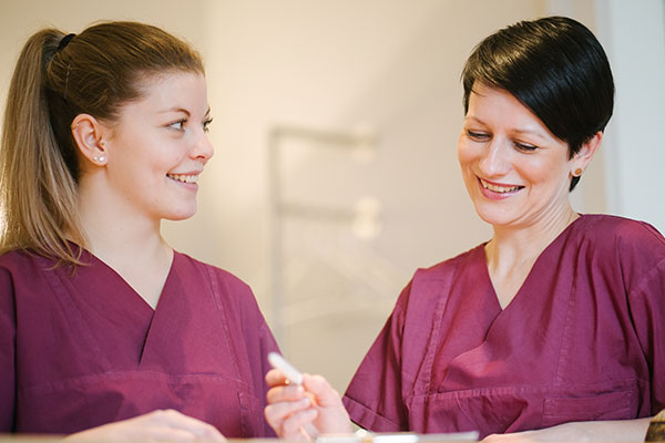 Mitarbeiterinnen der Praxisklinik bei der Vorbereitung von Patientenunterlagen für eine Halsstraffung mit Absaugung des Doppelkinn.